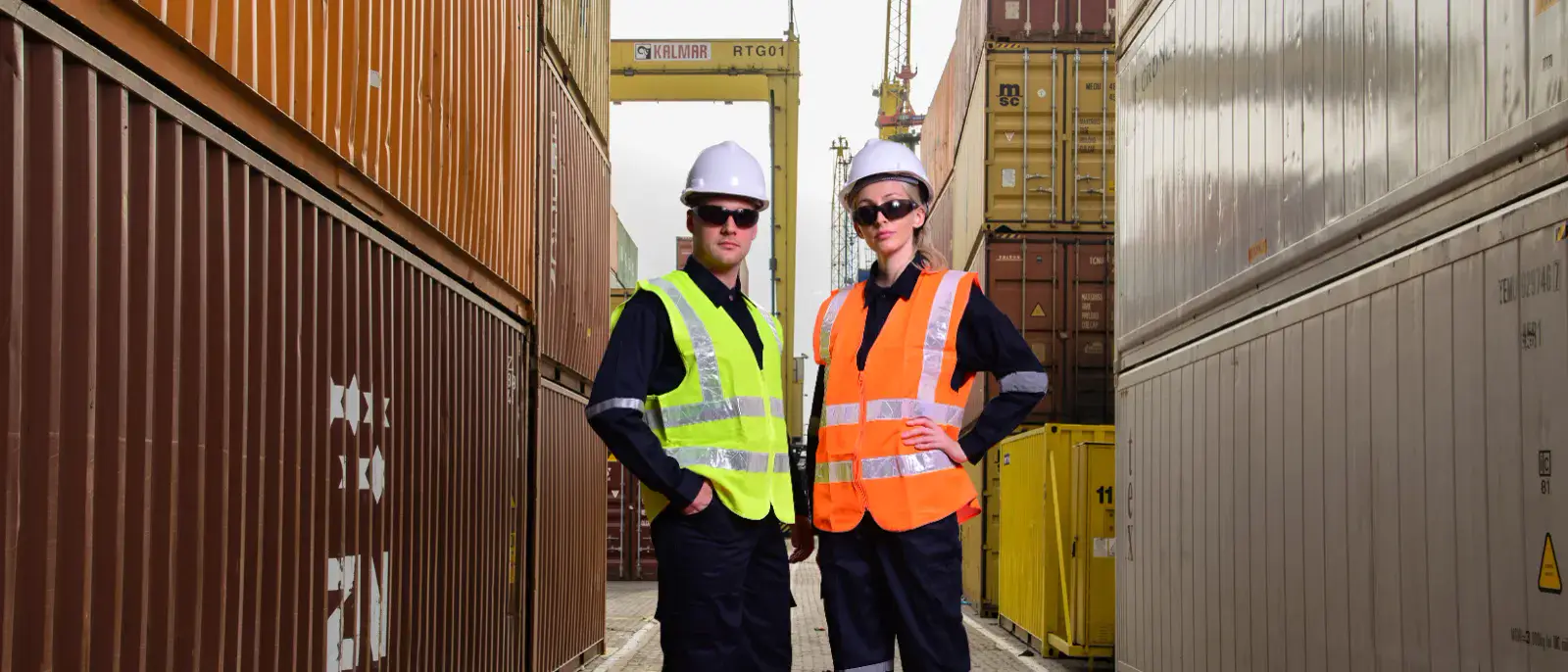 Two models in high-visibility safety vests and hard hats, composited into a container-port scene